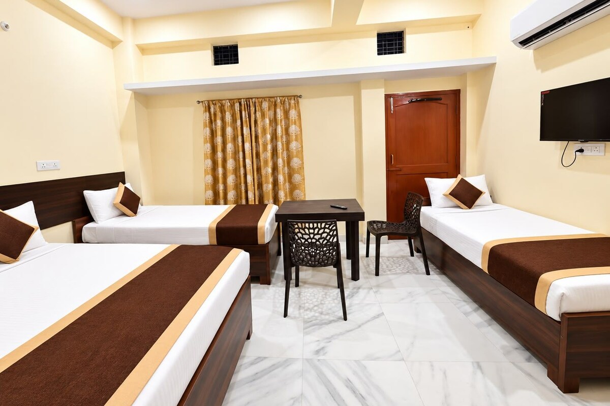 A hotel room with two beds, a desk, a chair, a television, and an air conditioning unit.