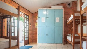 Een kamer met stapelbedden, een blauwe kast en een ventilator.
