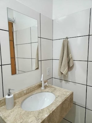 Une salle de bain avec un lavabo blanc, un miroir et une serviette accrochée au mur.