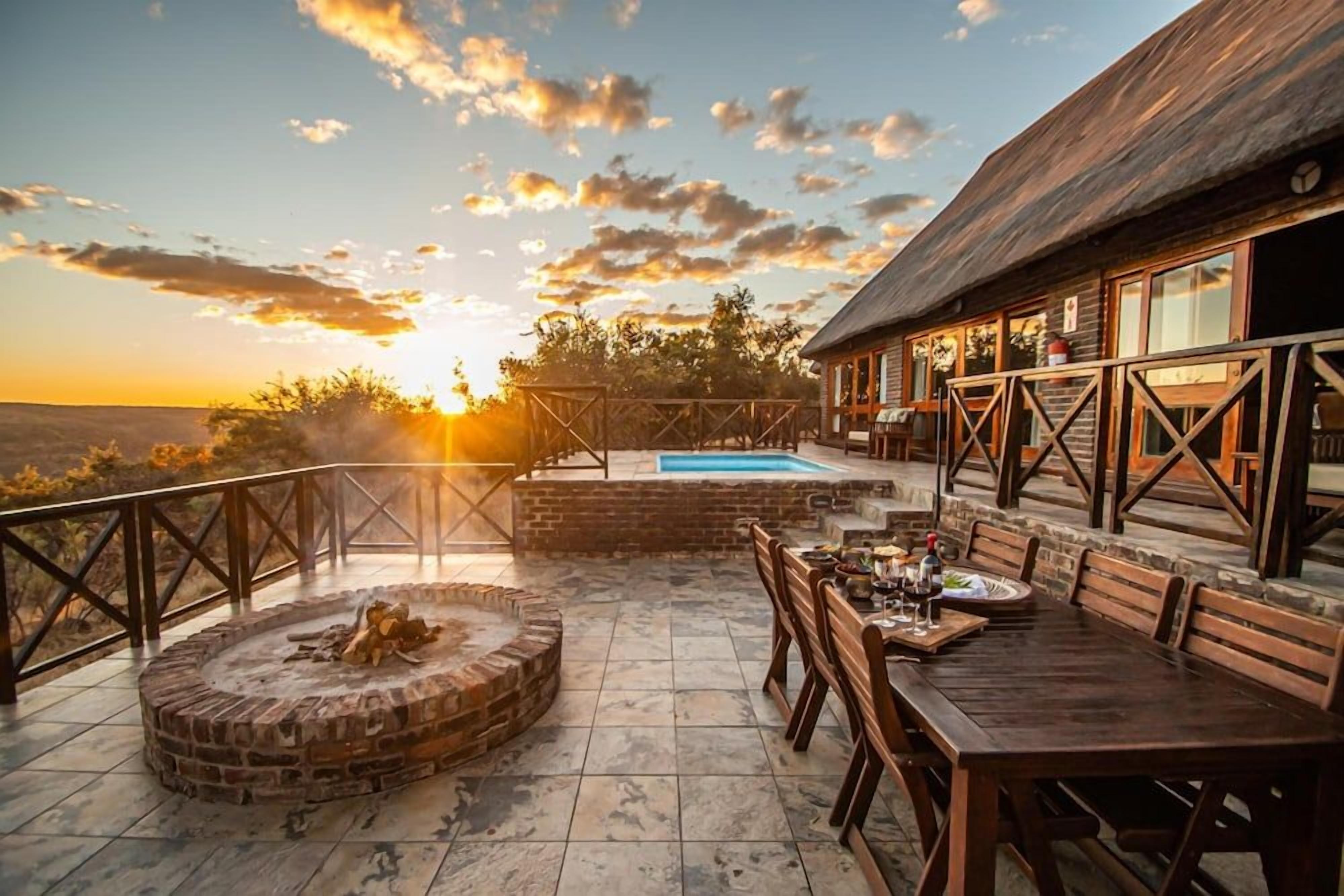 A wooden deck with a fire pit, outdoor seating, and a pool.