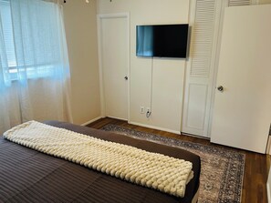 A bedroom with a bed, a television mounted on the wall, and a wardrobe. - 3BR Close to Historic Main Street-Low Cleaning Fee (Saint Charles)