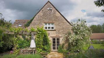 A stone house with a gabled roof, a small window, and a door.