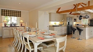 Una cocina amplia con armarios blancos, una mesa de comedor para seis personas y una isla grande con refrigerador.
