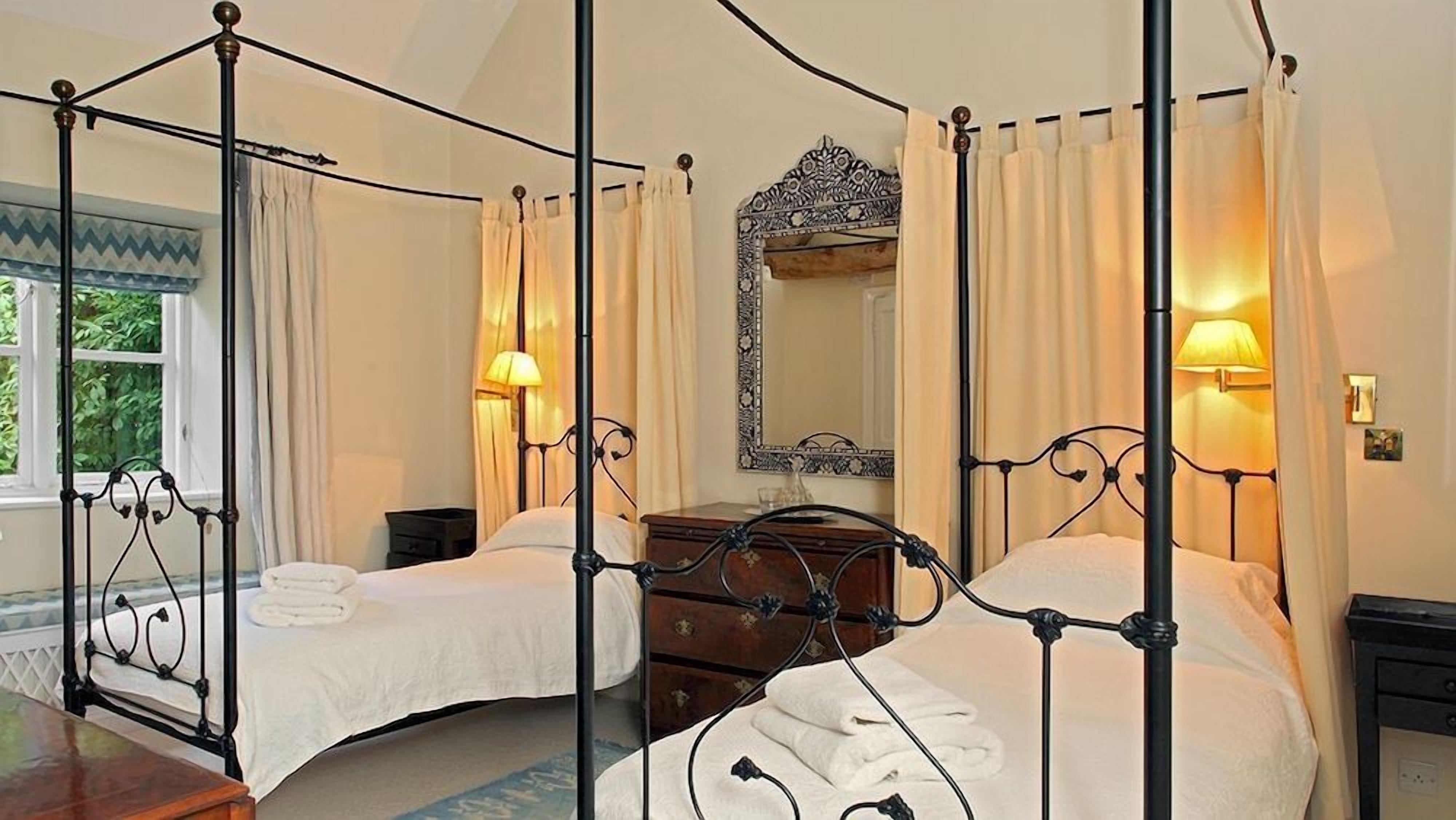 A four-poster bed with a wooden headboard, a bedside table, and a mirror above the bed.
