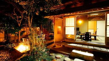 Un edificio de estilo japonés tradicional con un estanque de carpas koi, faroles de piedra y una terraza de madera.