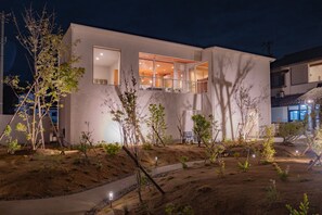 Ein modernes, zweistöckiges Haus mit großen Fenstern und einem einsehbaren Innenraum.