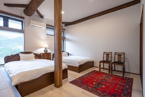 Ein Schlafzimmer mit zwei Betten, einer Holzbalkendecke, einem roten Teppich mit Muster und einem Nachttisch mit Lampe.