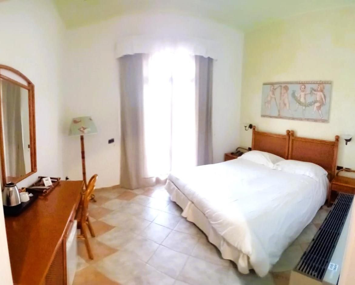 A hotel room with a bed, a desk, a chair, a lamp, and a window with curtains.