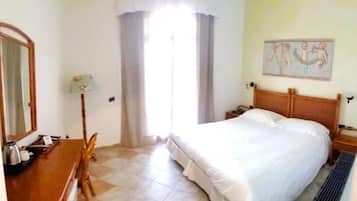 Ein Hotelzimmer mit Bett, Schreibtisch, Stuhl, Lampe und einem fensterbepflanzten Fenster.