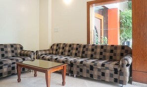A living room with a checkered sofa set and a glass coffee table. - Treebo Trend Brahma Regency (Pune)