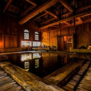 Uma grande piscina coberta com vigas de madeira e um reflexo.