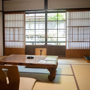 Um quarto japonês tradicional com tatames, uma mesa de madeira baixa e painéis shoji.