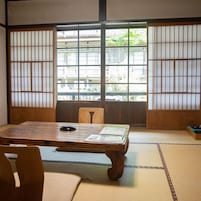 Um quarto japonês tradicional com tatames, uma mesa de madeira baixa e painéis shoji.