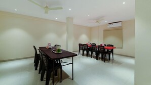 A spacious room with a dining table and chairs, ceiling fans, and recessed lighting. - Capital O 22922 Hotel Siddartha Grand (Vijayawada)