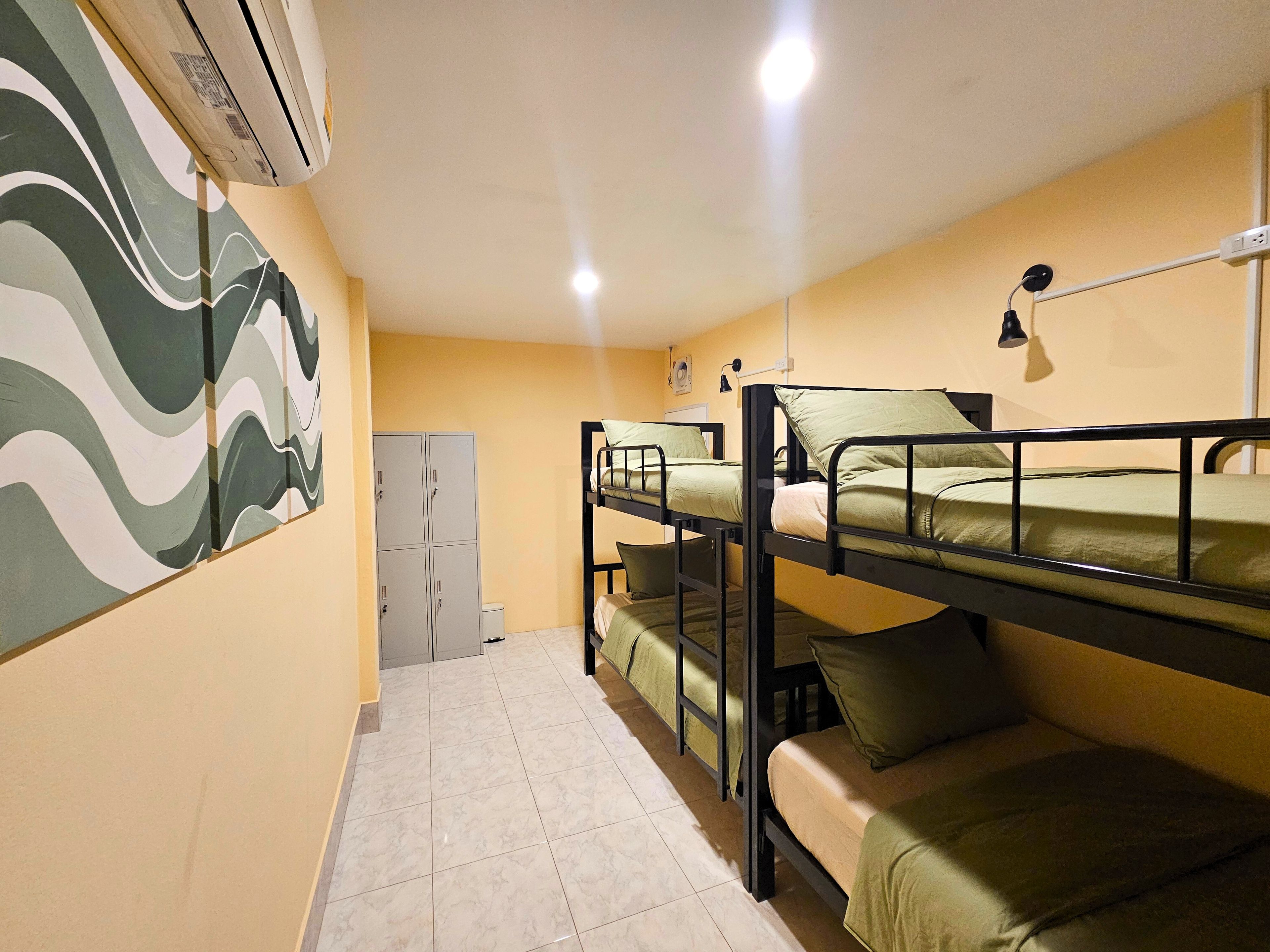 A dormitory room with bunk beds, a wardrobe, and a wall-mounted air conditioner.