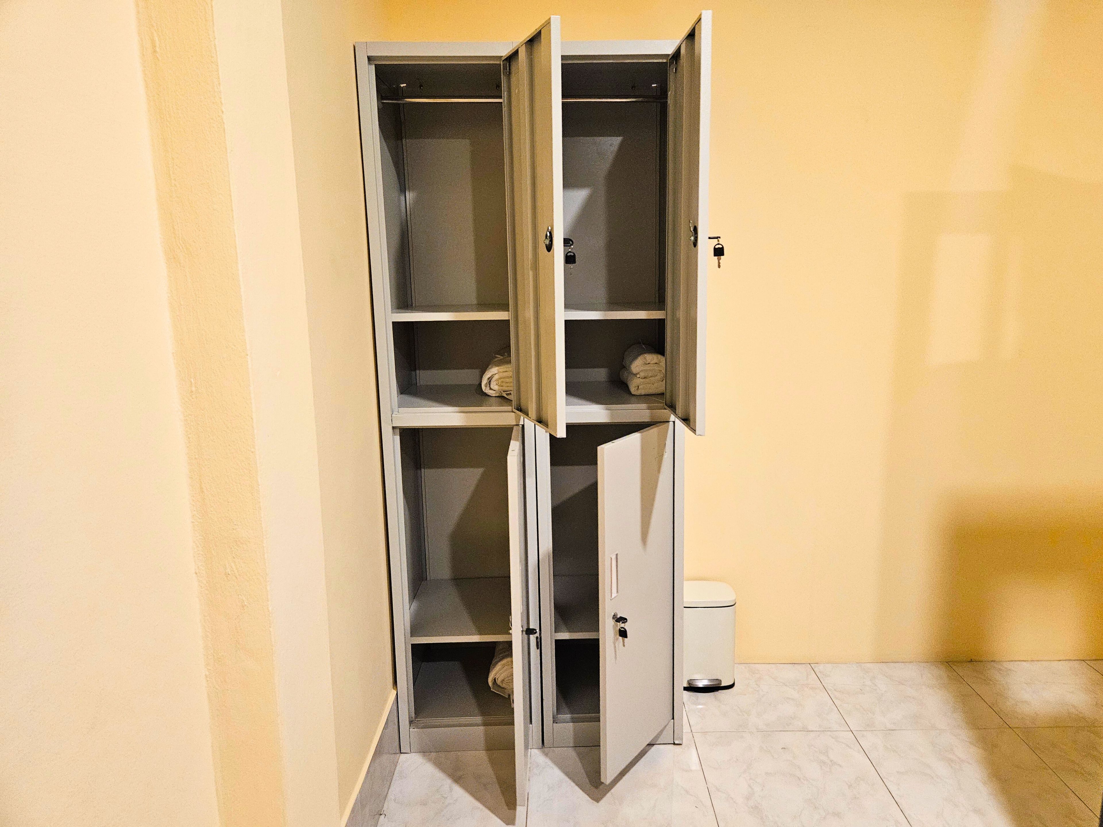 A storage cabinet with multiple shelves, a toilet, and a trash bin.