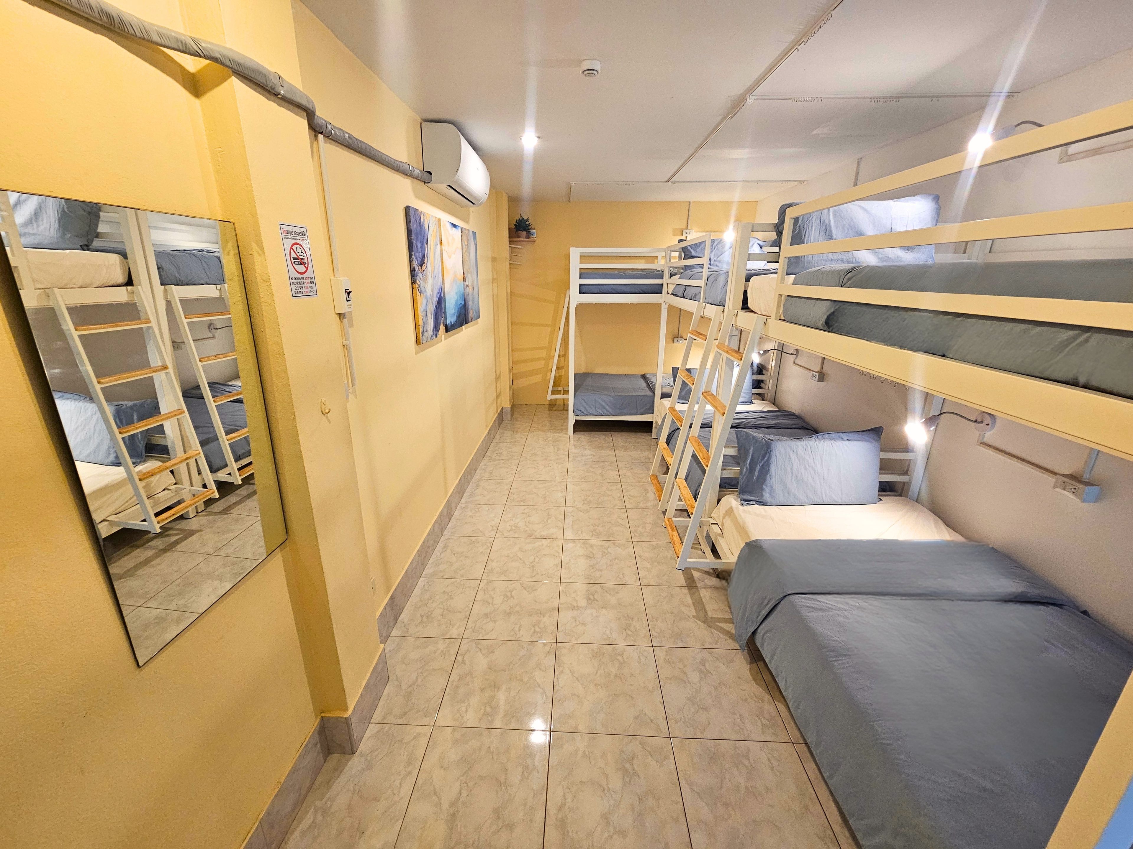 A corridor with bunk beds, a tiled floor, and a wall-mounted air conditioning unit.