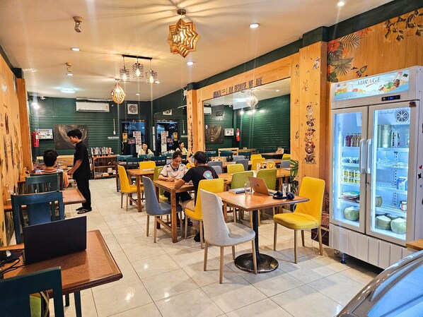 A restaurant interior with tables, chairs, and a refrigerator stocked with beverages.