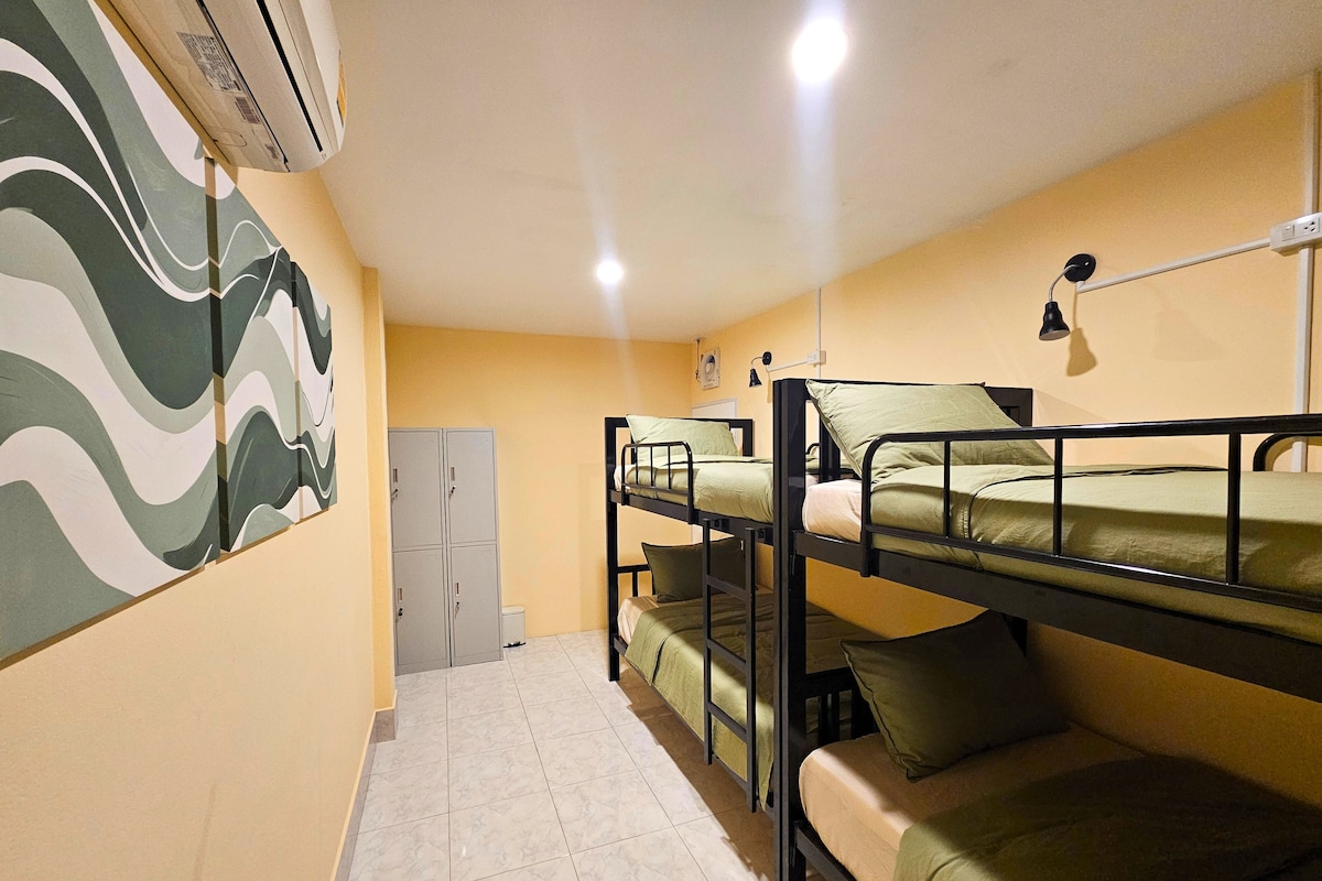 A dormitory room with bunk beds, a wardrobe, and a wall-mounted air conditioner.