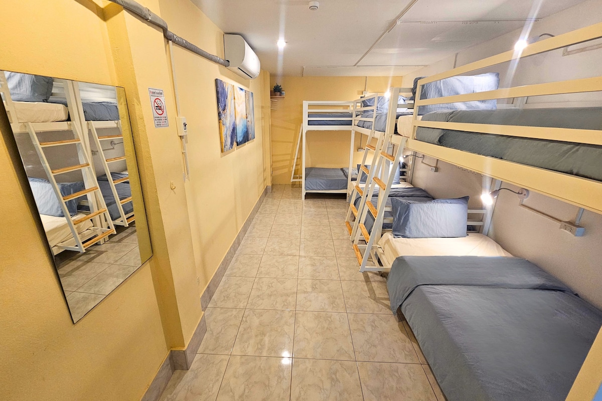 A corridor with bunk beds, a tiled floor, and a wall-mounted air conditioning unit.