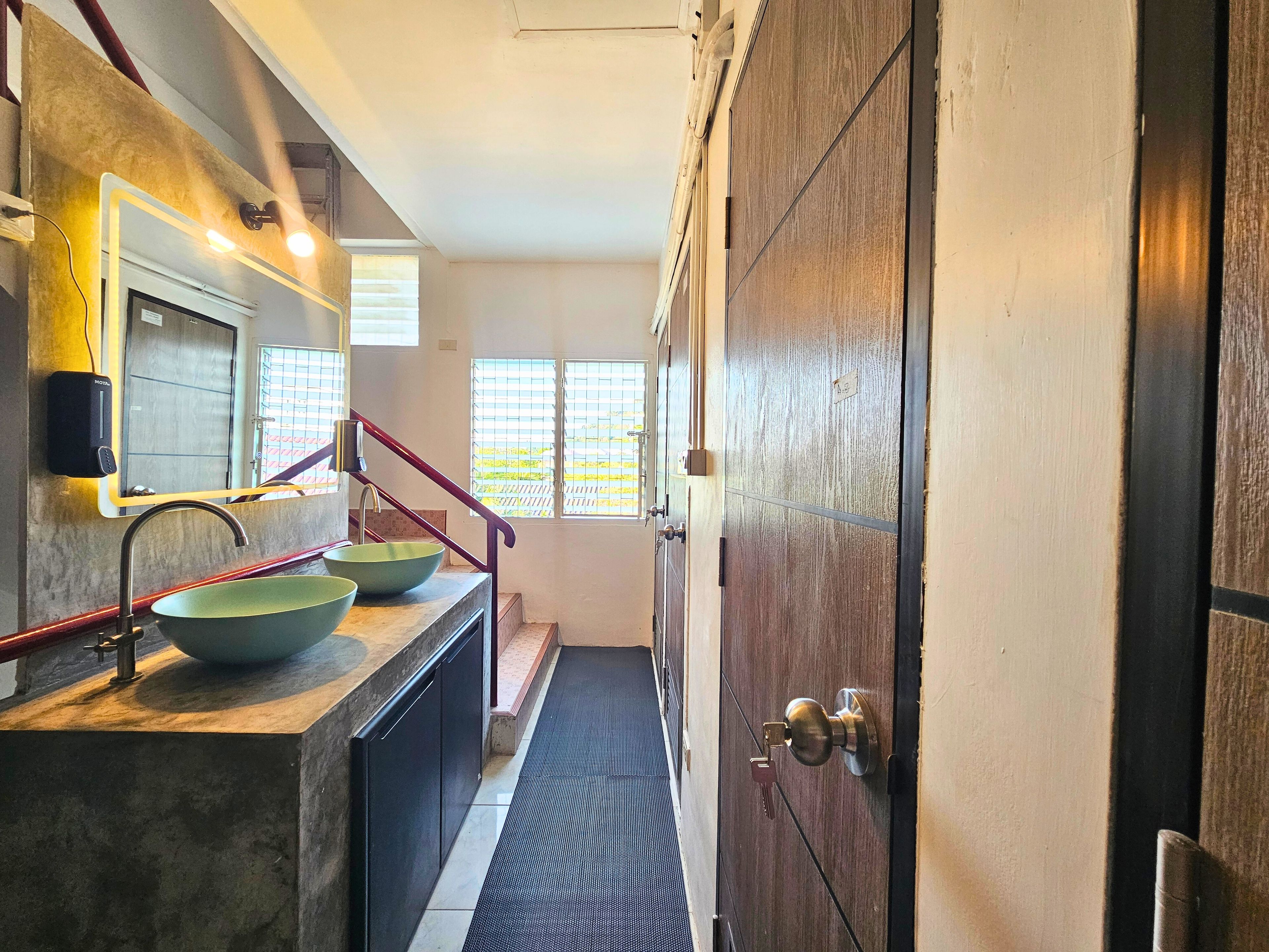 Un baño con lavamanos, espejo y puerta de madera.