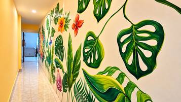 Un pasillo con un mural de plantas y flores tropicales.