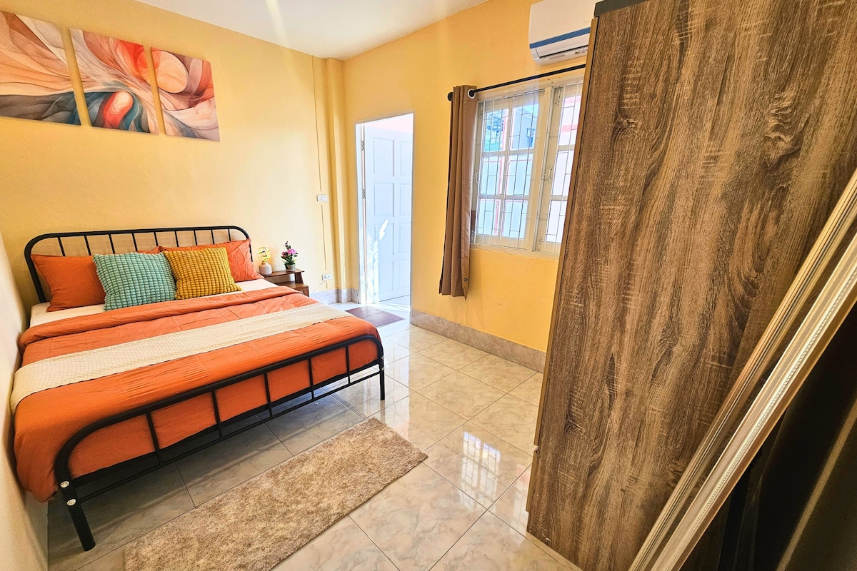 A bedroom with a bed, a nightstand, a window with curtains, and a door.