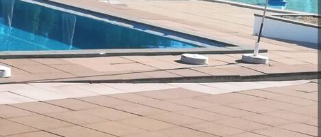 Un espace piscine avec des chaises longues et des parasols.