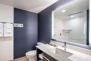 Un baño moderno con inodoro blanco, un espejo grande y un lavabo con grifo.