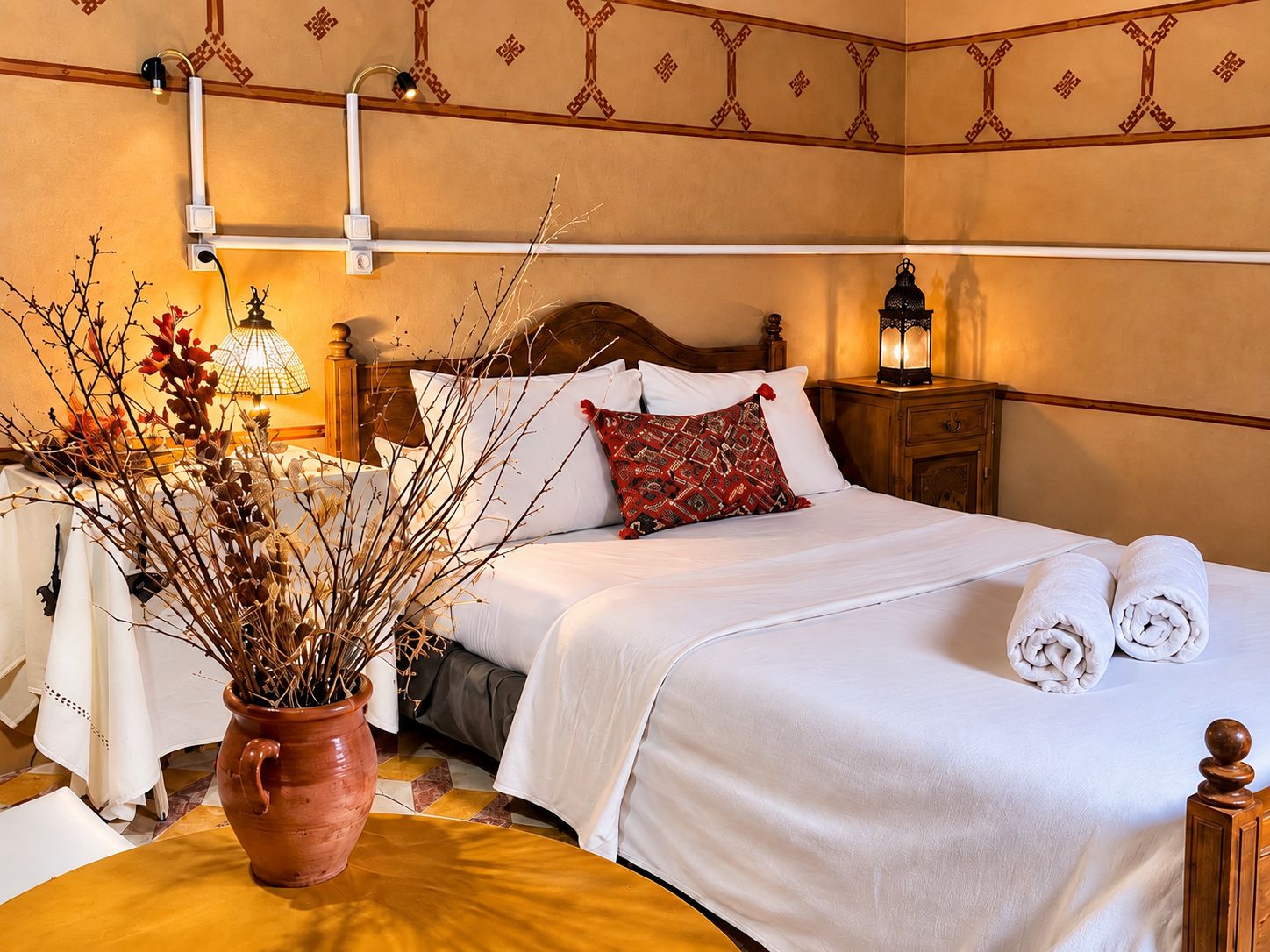 Une chambre d’hôtel comprenant un lit, une table de chevet, une lampe et un vase décoratif.