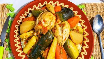 A plate of food with vegetables and a chicken leg, accompanied by two bowls of olives.