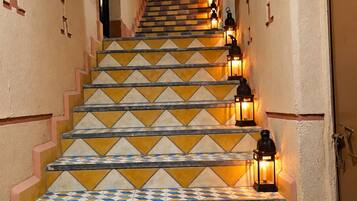 A staircase with patterned tiles and wall-mounted lanterns.