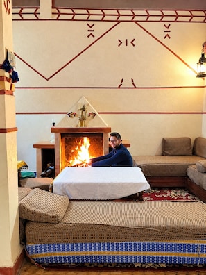 A room with a fireplace, a sofa, and a patterned rug.