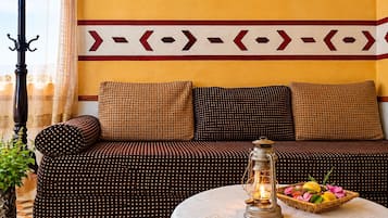 A room with a sofa set, a table with a lantern, and a decorative wall pattern.