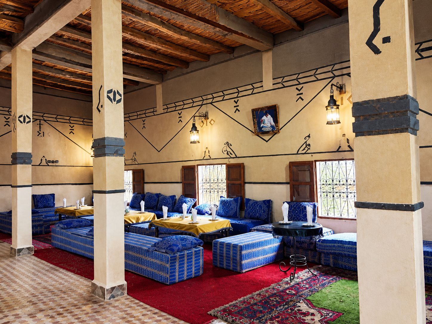 A room with blue patterned sofas, a red carpet, and a patterned floor.