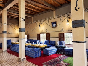 A room with blue patterned sofas, a red carpet, and a patterned floor. - Hôtel panoramique de la vallée (Ait Sedrate Jbel El Soufla)