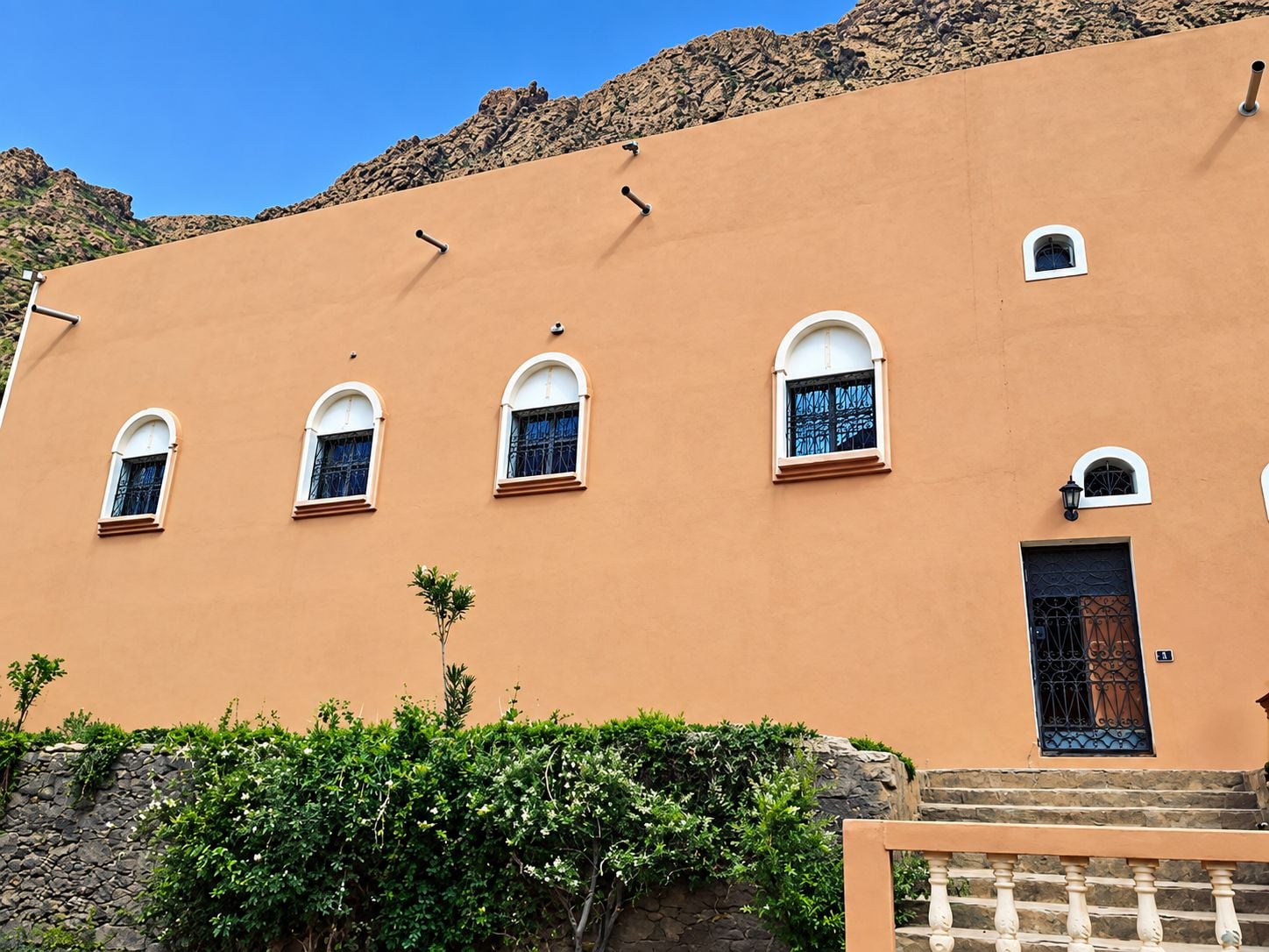 A building with a flat facade, multiple arched windows, and a small door.