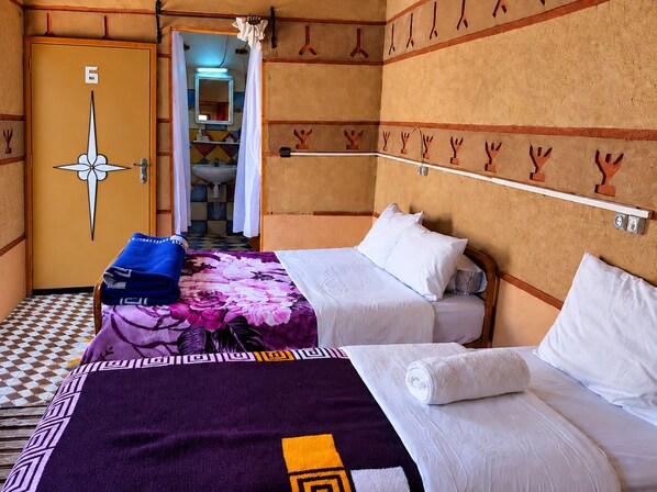 A hotel room with two beds, a bathroom with a sink, and a door marked with the number 6.