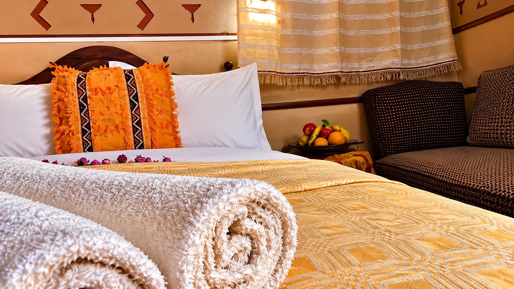 Una habitación de hotel con una cama, una mesita de noche con fruta y un sofá.