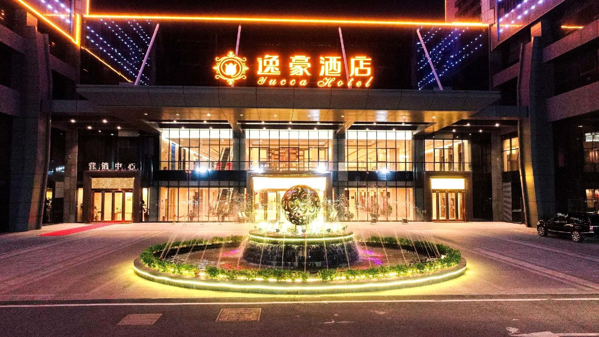 A hotel entrance with a water feature in the center, illuminated by lights.