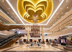 A spacious lobby with a central chandelier, multiple levels, and a large hand sculpture.