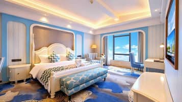 Habitación de hotel con una cama grande, una zona de estar, un televisor y vista al cielo.