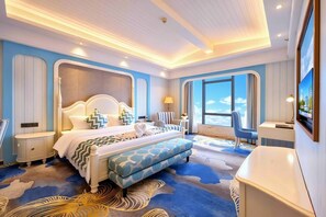 A hotel room with a large bed, a seating area, a TV, and a view of the sky. - Yucca Hotel (Jiangmen)