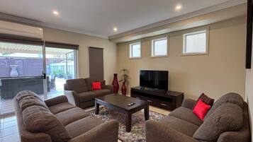 A living room with a sofa set, a coffee table, a TV, and a sliding glass door leading to an outdoor area.