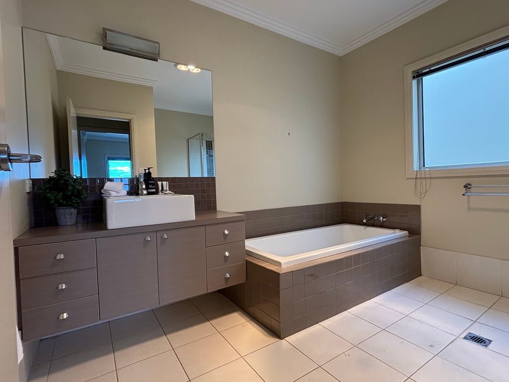 A bathroom with a bathtub, a sink, and a mirror.