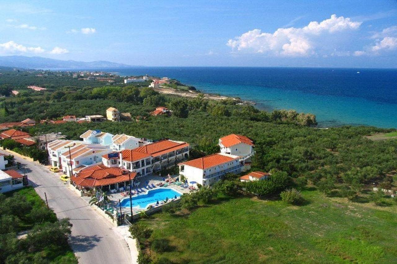 Un hotel frente al mar con varias construcciones, una piscina y vistas al océano.