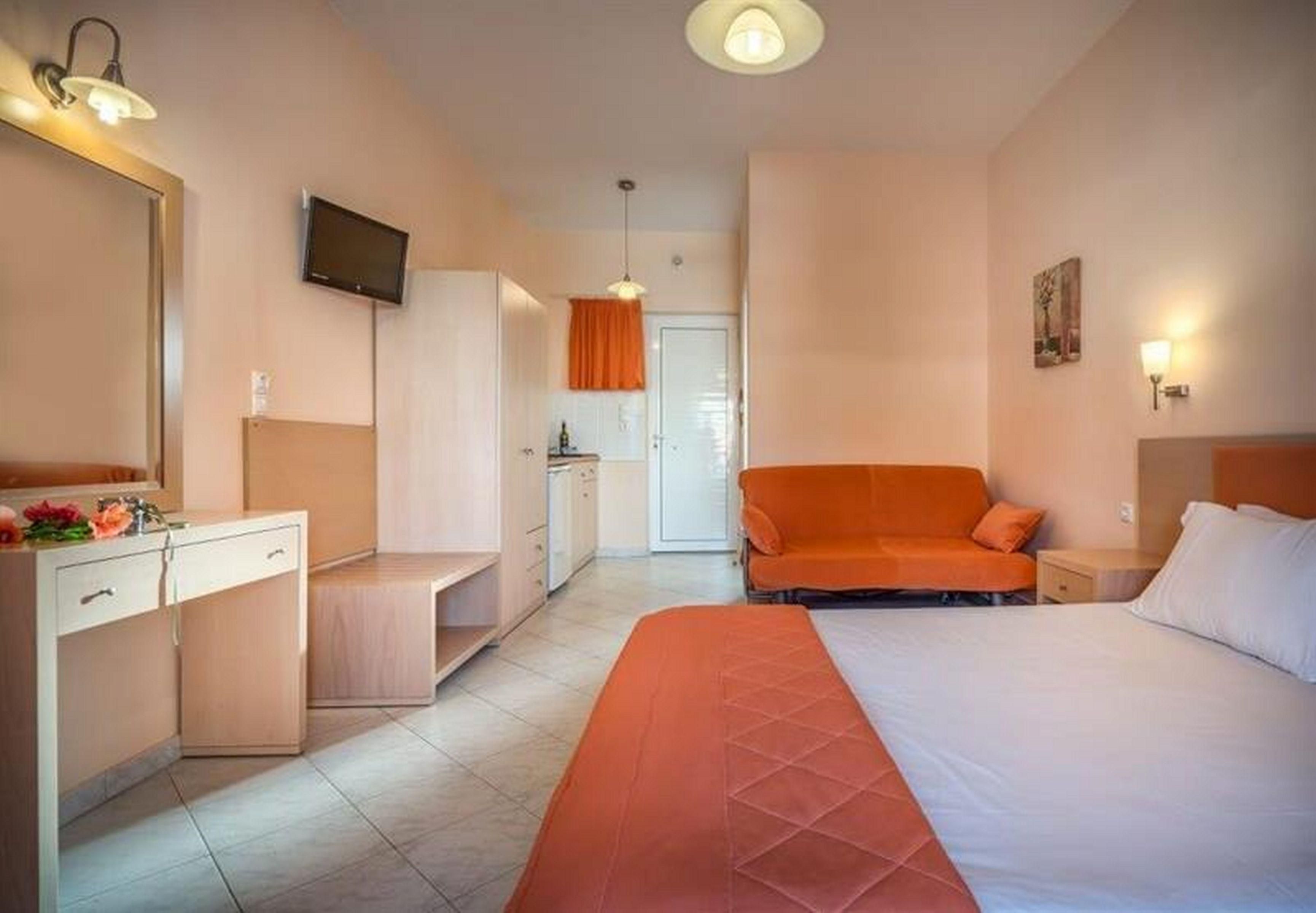 A hotel room with a bed, a desk, a television, and a sofa.