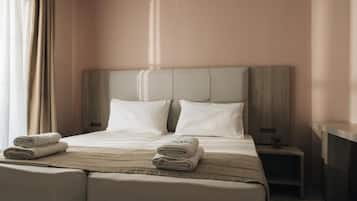 Een hotelkamer met een groot bed, twee kussens, een nachtkastje en een bijzettafeltje met een lamp.
