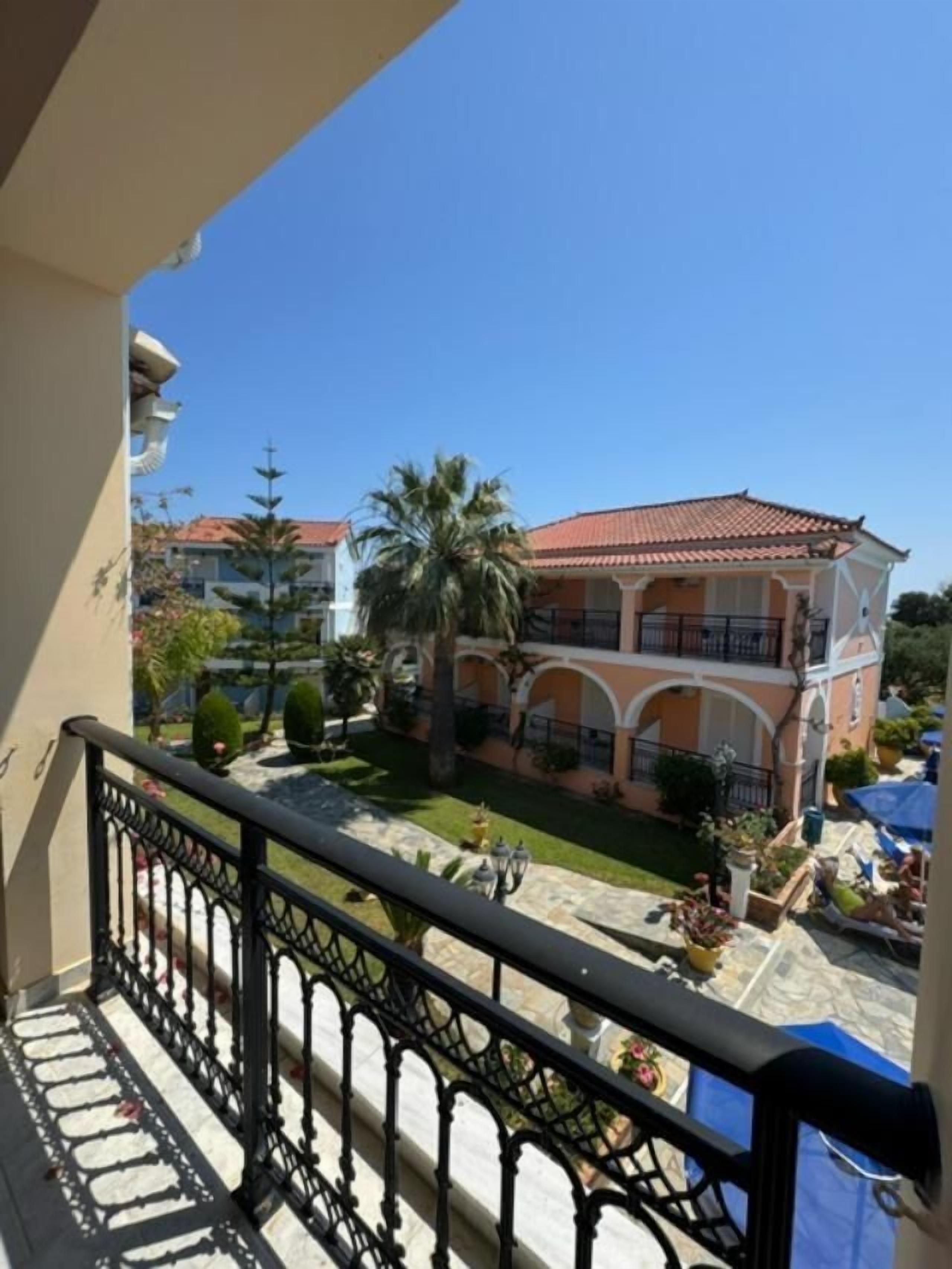 A balcony with a view of a building with a red-tiled roof and a courtyard.