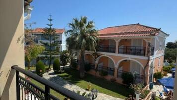 A balcony with a view of a building with a red-tiled roof and a courtyard.